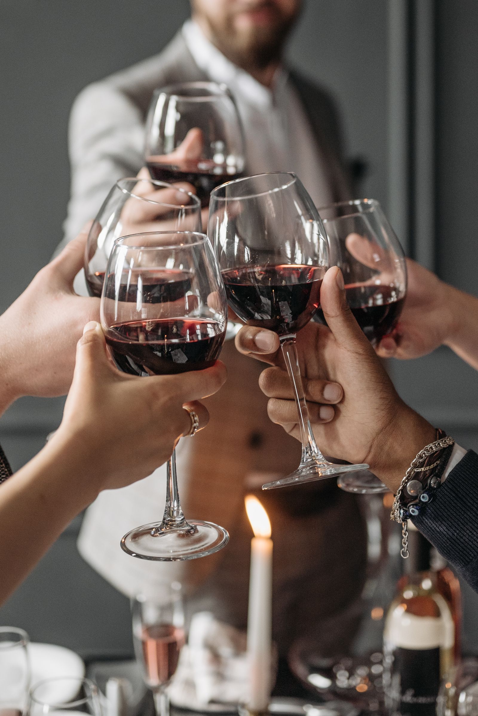 Des verres de vin rouge levés à la lumière des bougies