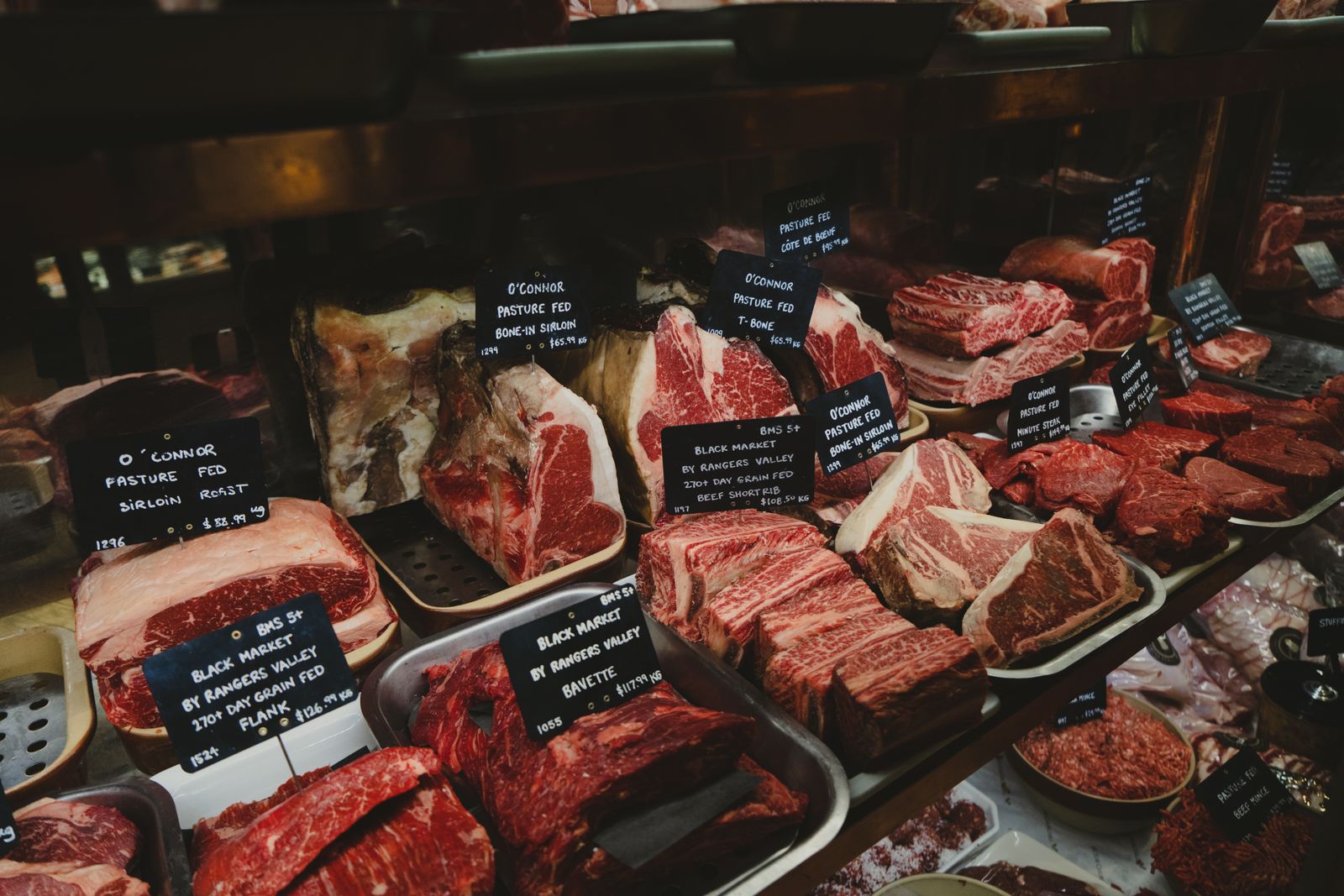 Le comptoir de la boucherie et ses pièces de viande étiquetées à la craie