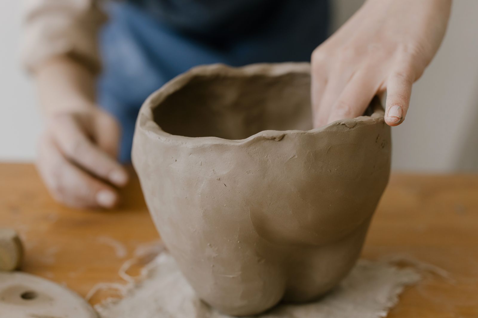 Des mains façonnant un pot de terre dans l'atelier de céramique