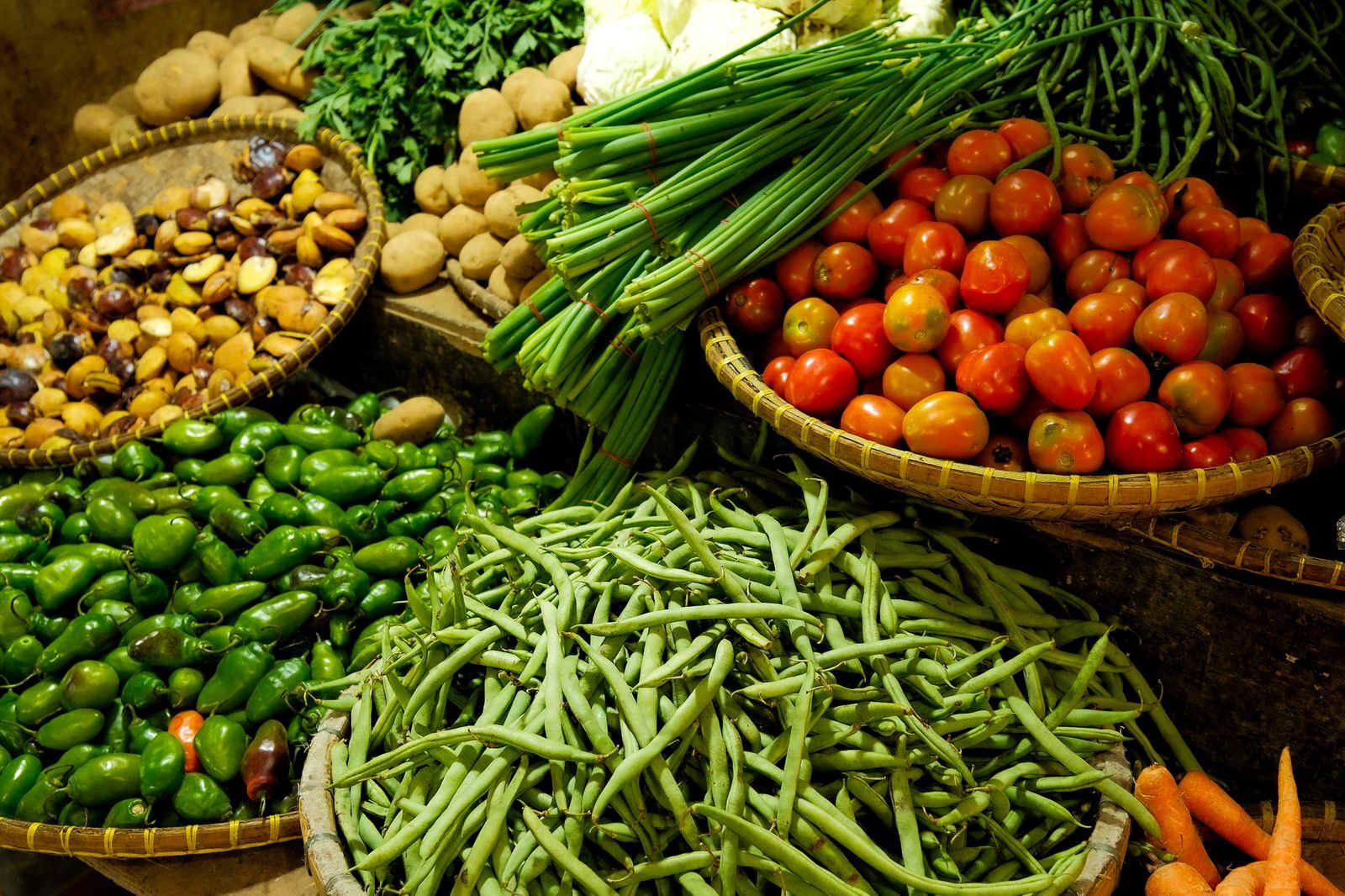 Les paniers d'osier remplis de haricots verts, de tomates et de pommes de terre sur un étal