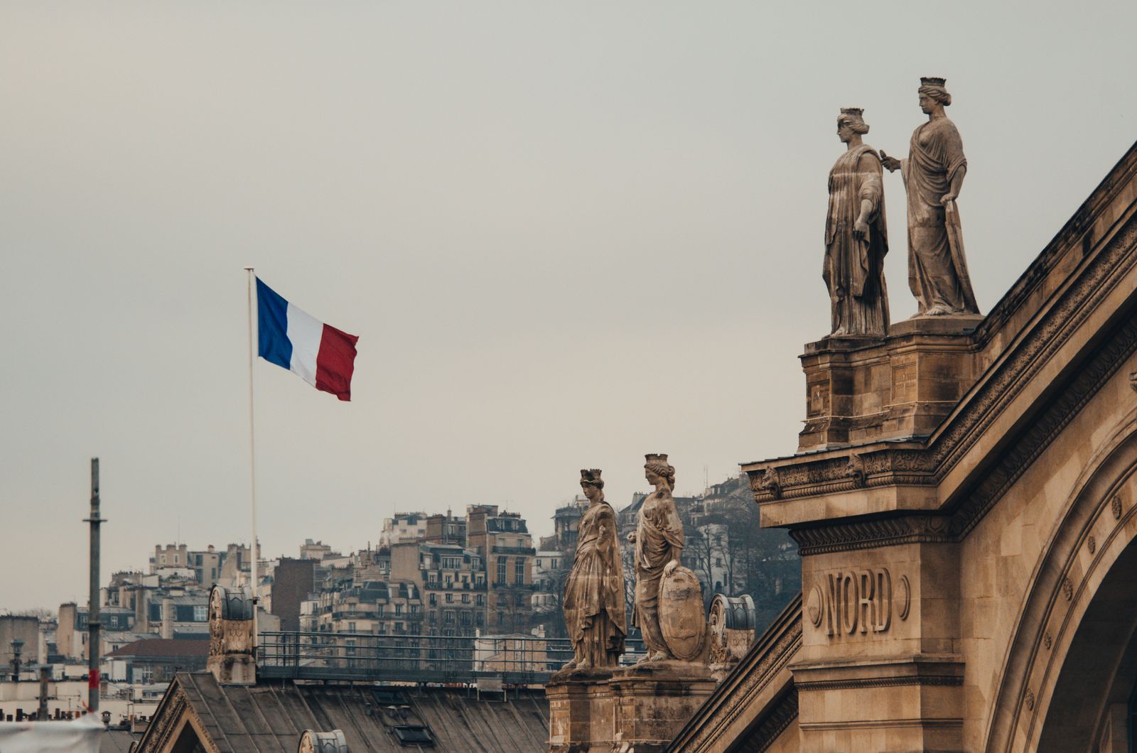 La façade de pierre de l'hôtel de ville, ses statues et le drapeau tricolore
