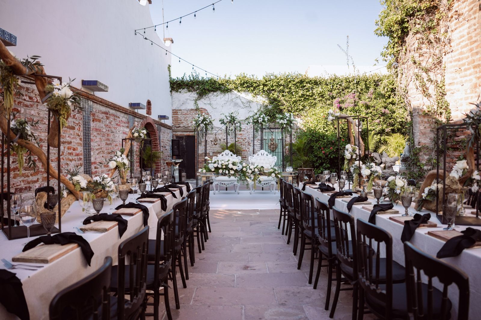 Les longues tables d'un mariage dressées en plein air, guirlandes et feuillages
