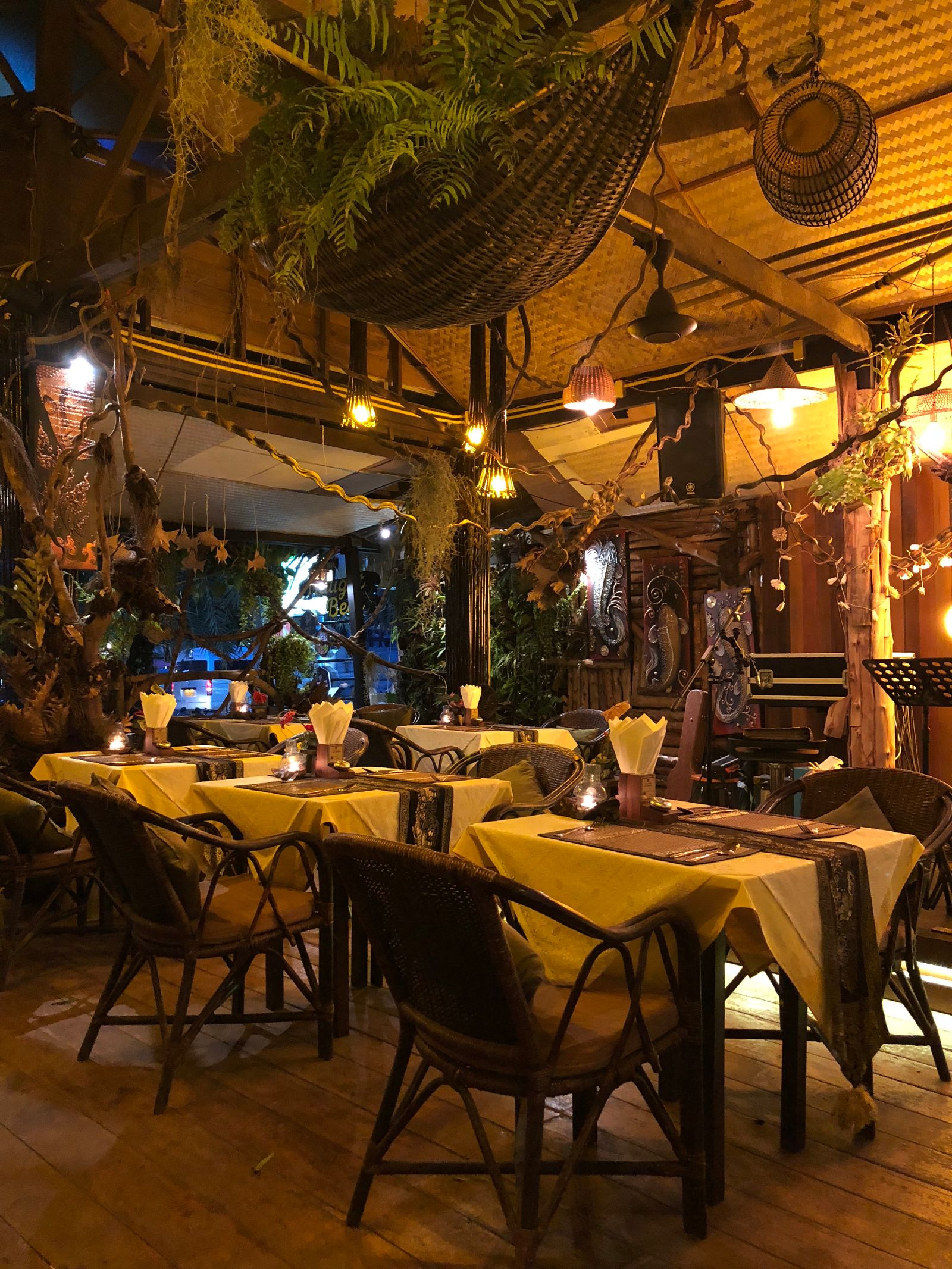 La salle du restaurant dressée le soir, nappes claires et lumières chaudes