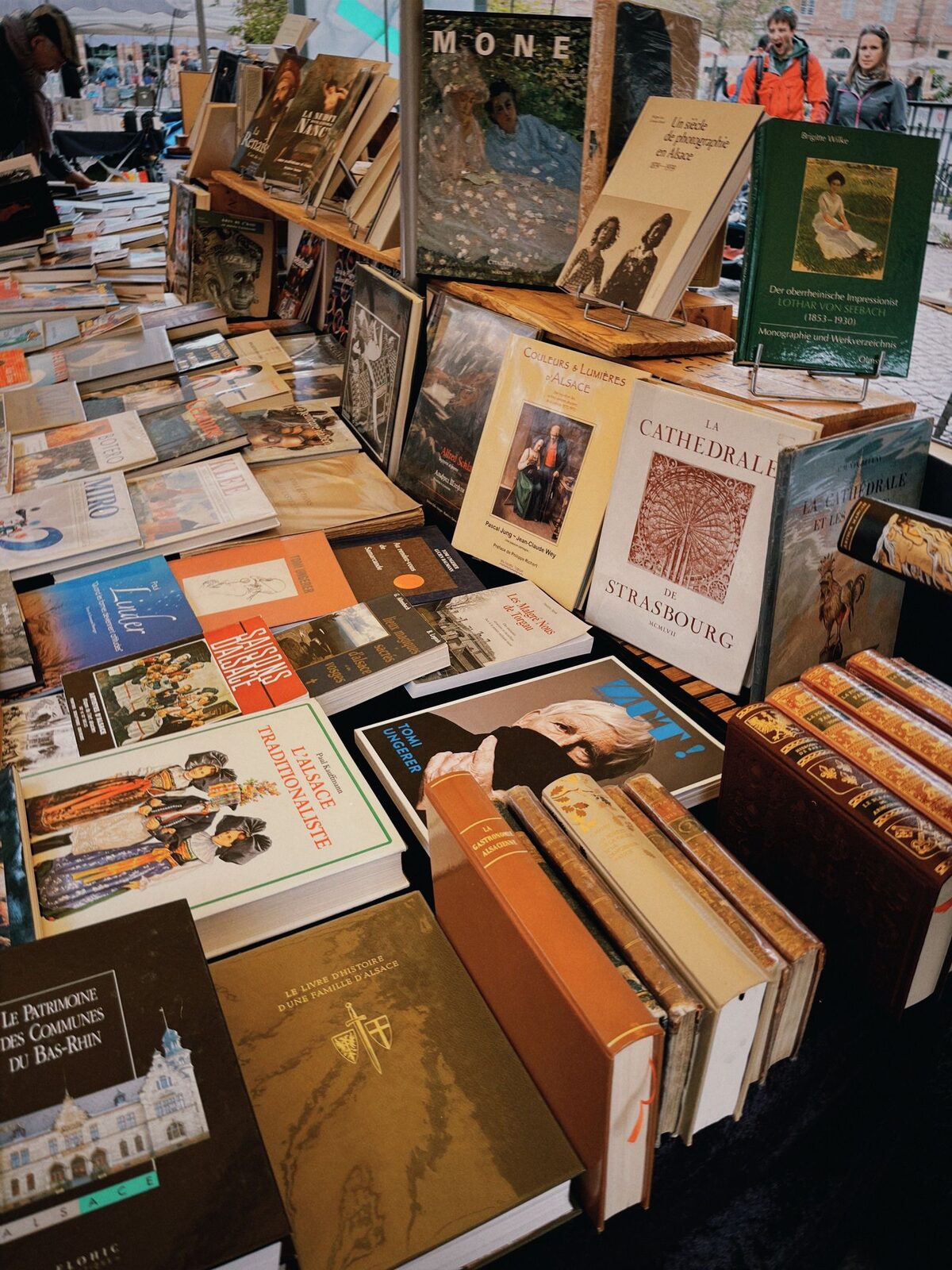 Les livres anciens et les cartes postales d'un étal de bouquiniste, prix à l'ardoise