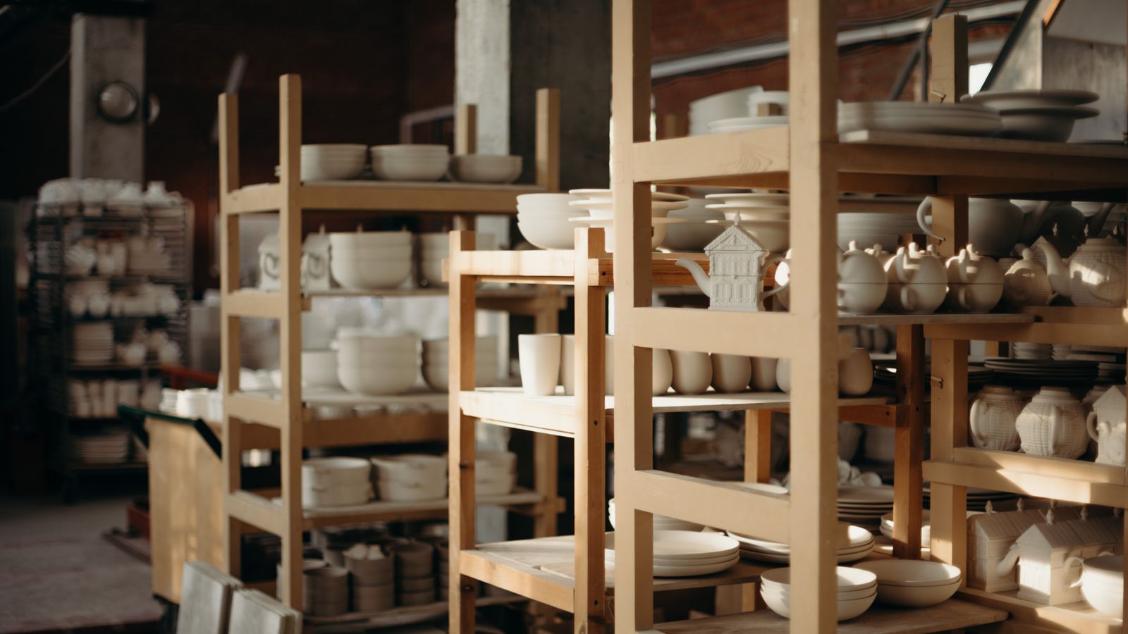 Étagères en bois chargées de céramiques blanches d'atelier
