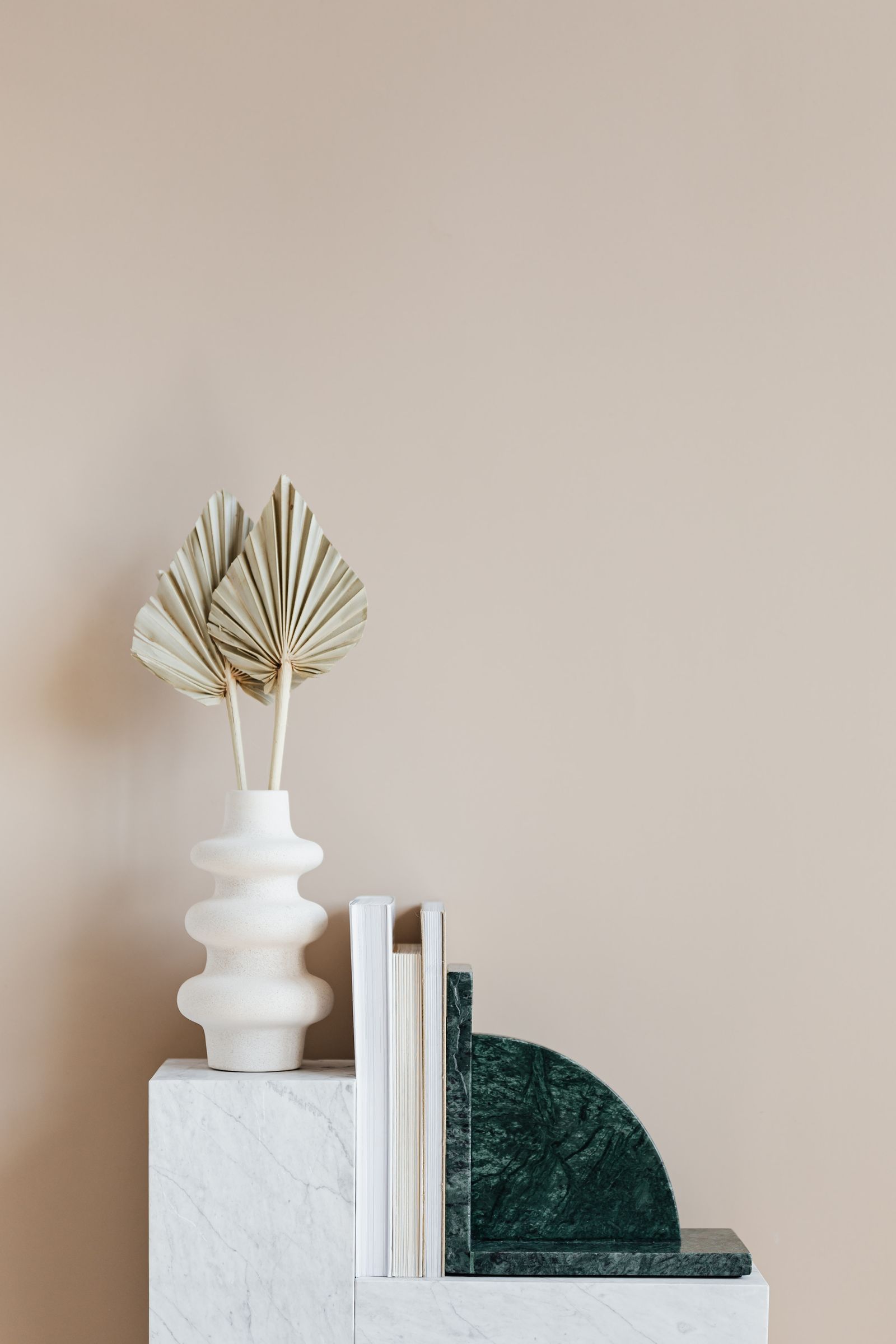 Vase strié blanc et palme séchée sur une étagère