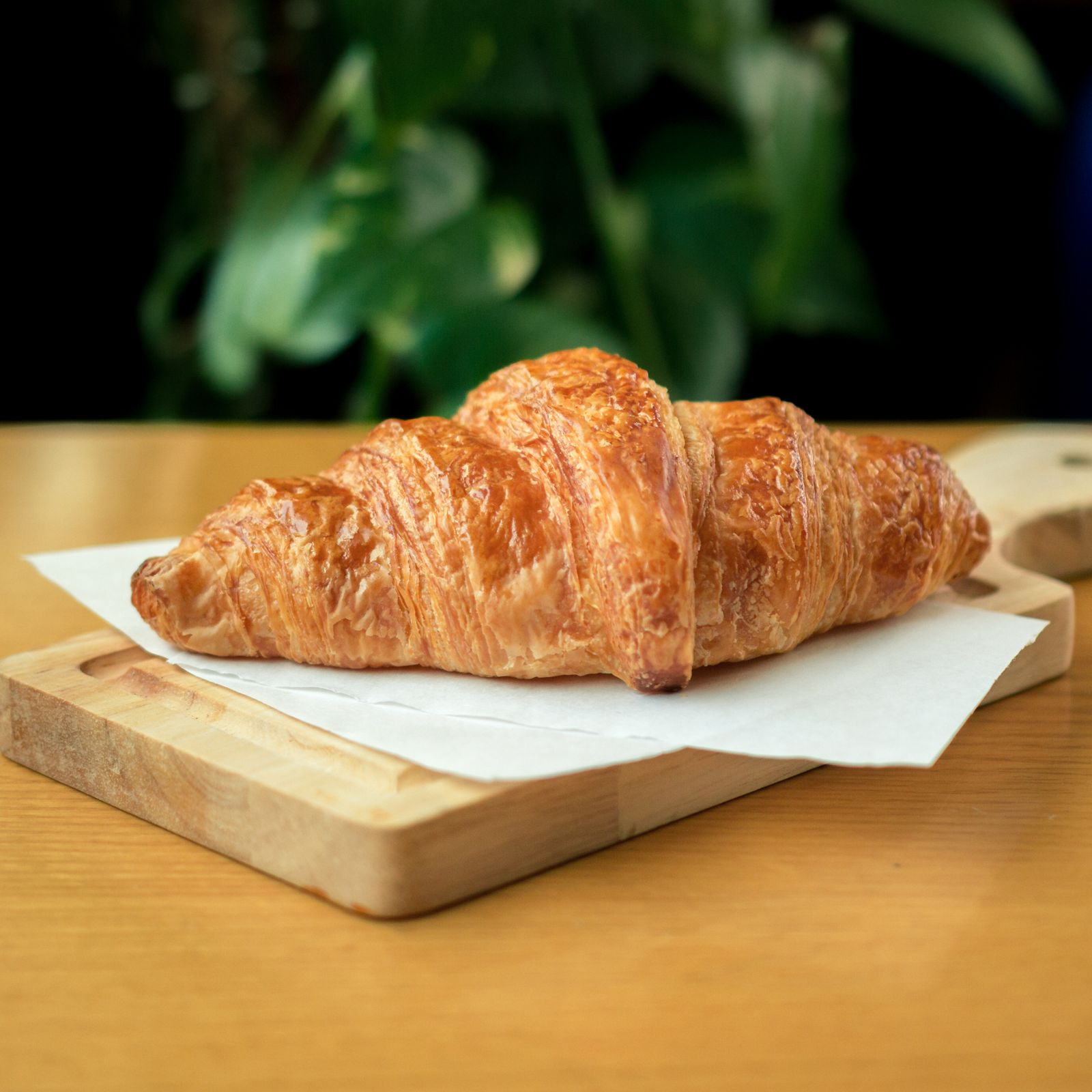 Croissant au beurre sur planche, lumière naturelle