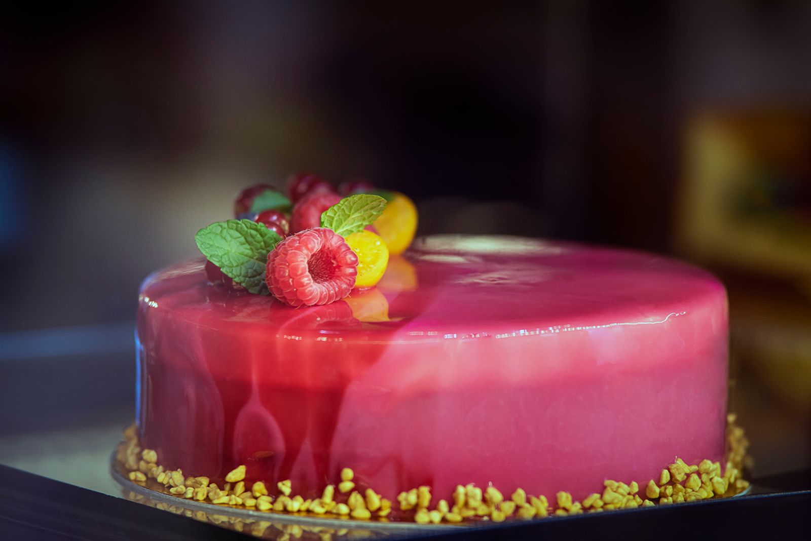 Entremets framboise au glaçage miroir, éclats de pistache autour du socle