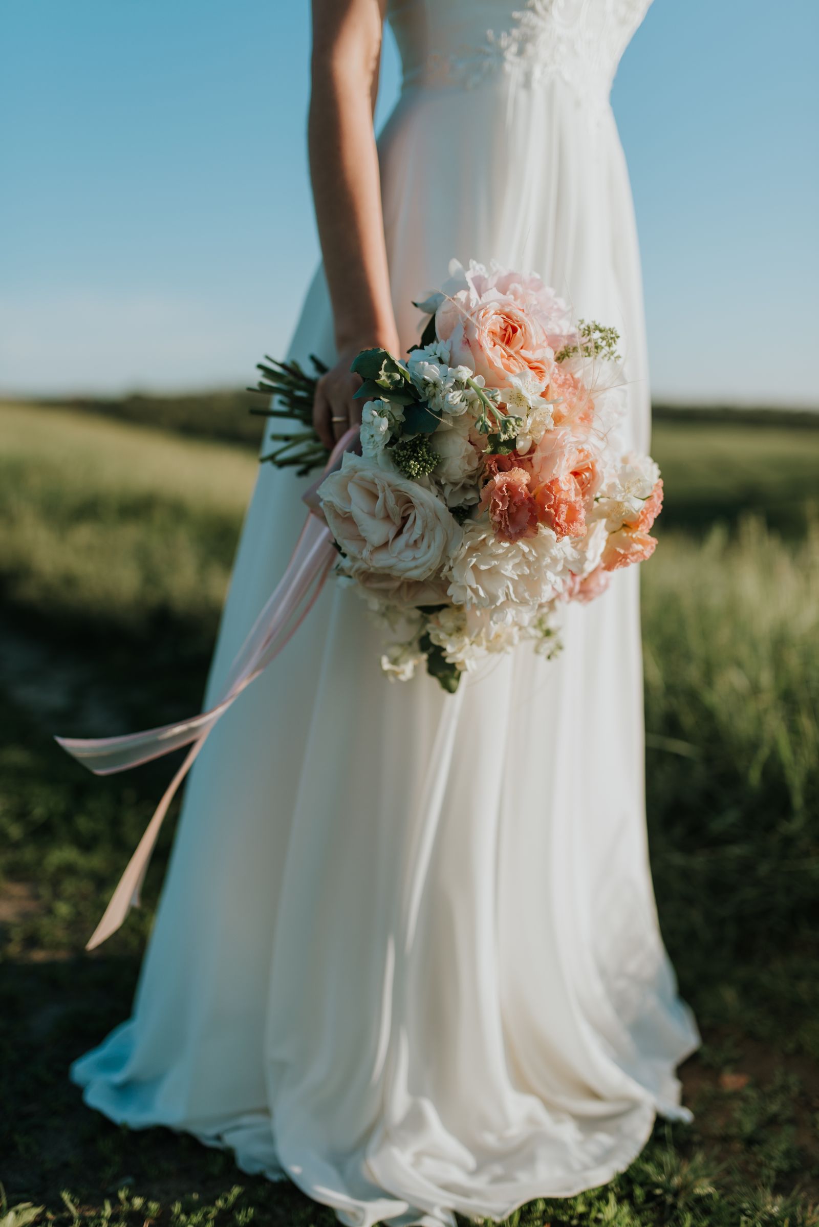 La mariée dans un champ, bouquet le long de la robe